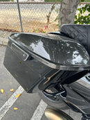 Black motorcycle hard saddlebag with glossy carbon-fiber lid and diamond-stitched leather seat
