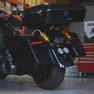 Black touring motorcycle rear with hard saddlebags and gold shocks