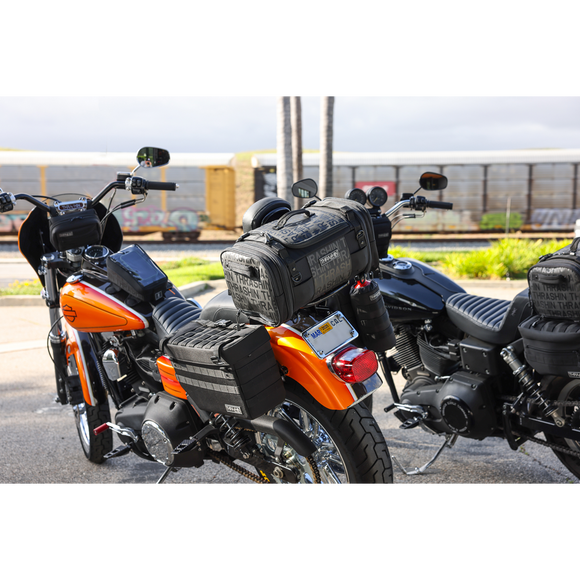 Thrashin Supply Co. Passenger Bag in black ballistic nylon with expandable dual-zipper design and hi-viz orange interior