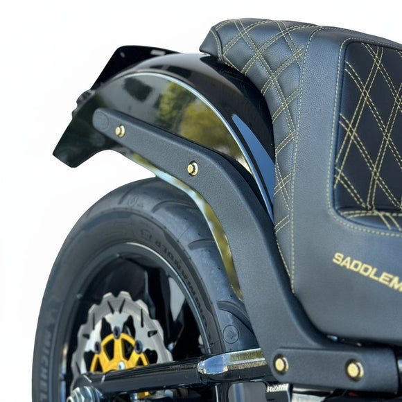 Close-up of Bamco ARP stainless steel bolts (gold) securing rear fender and strut on 2018+ Harley‑Davidson Softail, black quilted seat and rear wheel visible