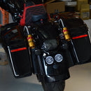 Black touring motorcycle rear with hard saddlebags, red-stitched leather seat and Ohlins shocks