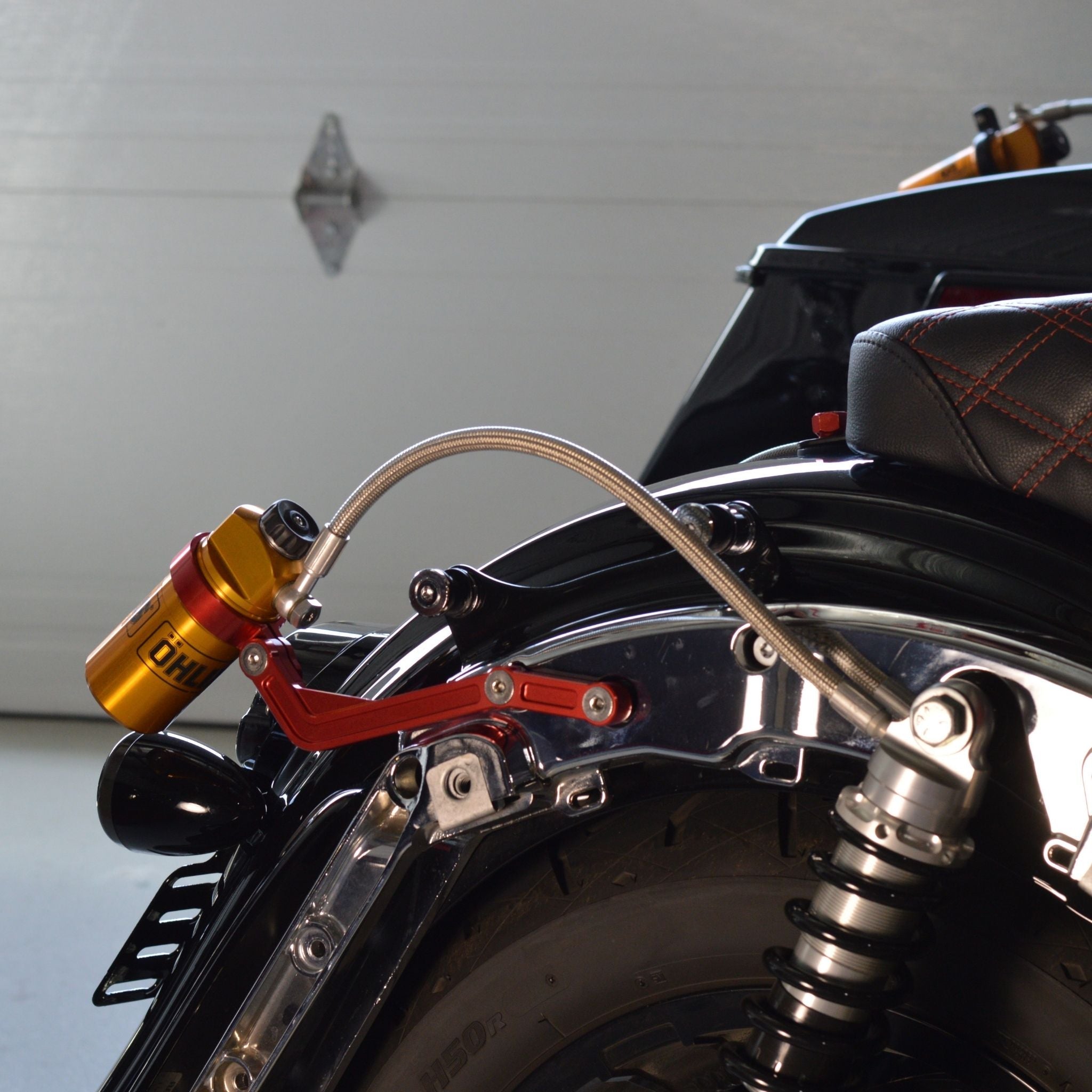 Gold Ohlins remote reservoir motorcycle shock with red bracket and braided hose