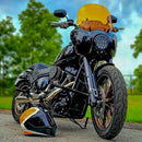Black custom cruiser motorcycle with amber windshield and matching orange-black helmet