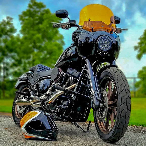 Black custom cruiser motorcycle with amber windshield and matching orange-black helmet