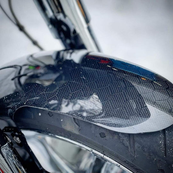 Carbon fiber motorcycle front fender close-up with chrome fork and tire