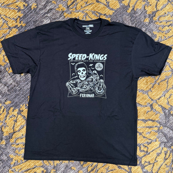 A black short-sleeve graphic t-shirt featuring a white and gray 'Speed-Kings' motorcycle print, laid flat on a textured yellow and gray patterned carpet.