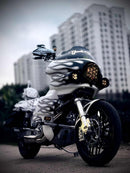 A custom Harley Davidson motorcycle with RWD V-Twin parts sits parked in front of a large building