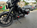 Black custom bagger motorcycle with front fairing, hard saddlebags, and red accent pegs
