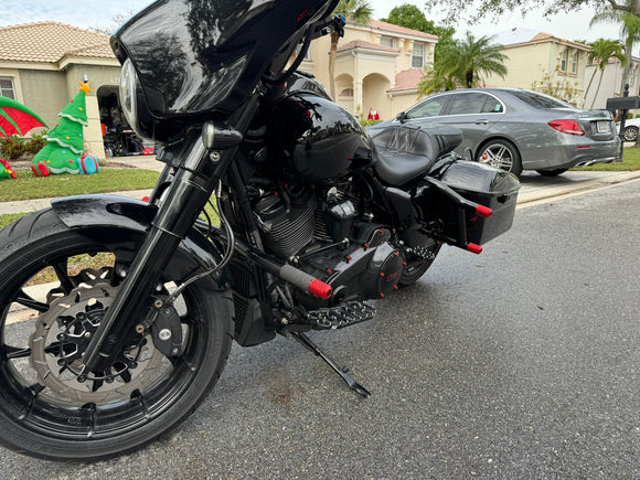 Black custom bagger motorcycle with front fairing, hard saddlebags, and red accent pegs
