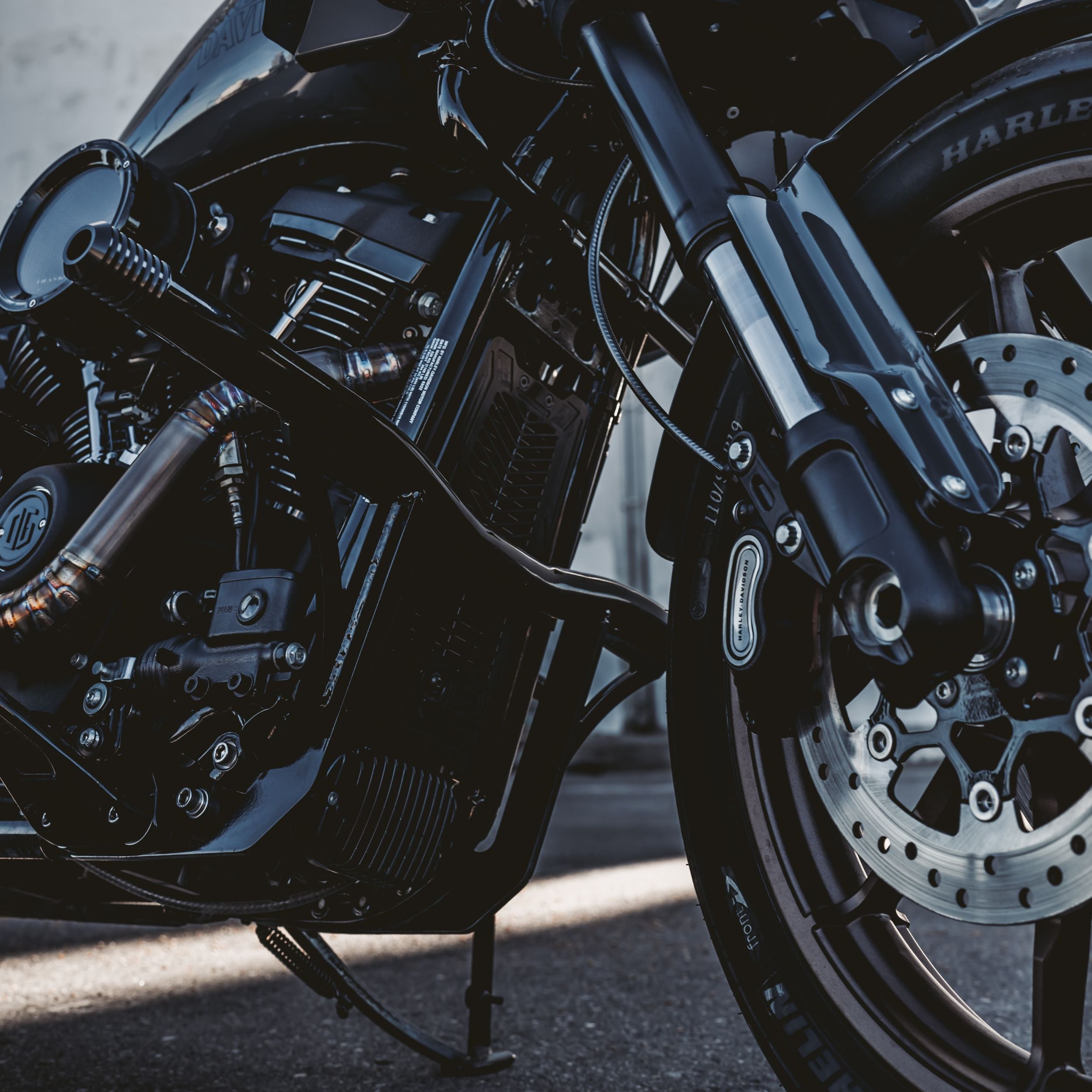 Black OG highway peg crash bar installed on Harley-Davidson M8 Softail, front engine and wheel close-up