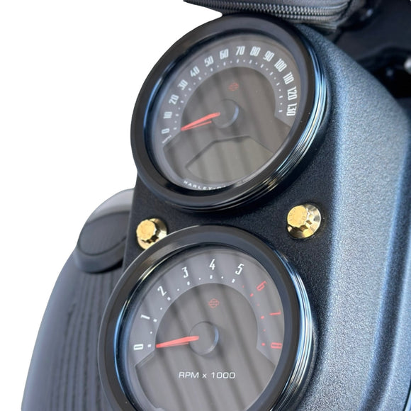 Close-up of Harley‑Davidson gauge cluster with two gold ARP 12‑point Bamco stainless‑steel bolts