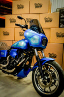 A custom blue RWD V-Twin motorcycle with a fairing, LED headlight, and custom paintwork, parked in front of stacked RWD branded boxes.