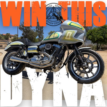 A custom silver and black motorcycle with lime green accents, set against a desert background with large orange and white text overlays reading 'WIN THIS DYNA'.