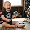 Baby in a speed kings onesie holding a wrench
