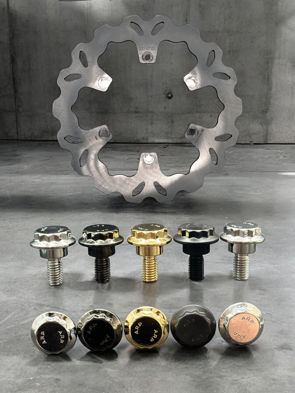 ARP stainless steel Harley-Davidson rotor bolts by Bamco in chrome, black and gold finishes arranged in front of a motorcycle brake rotor